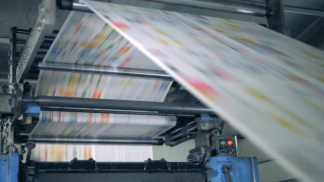 Publishing house unit with paper rolling through the machine. Printing newspapers in typography.