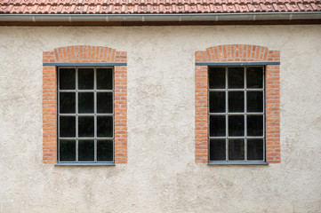 Two windows on a grey plaster wall