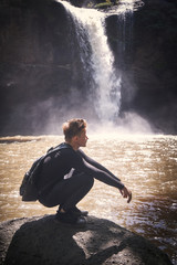 Obraz premium Man stand on the rock against waterfall streaam in rain season