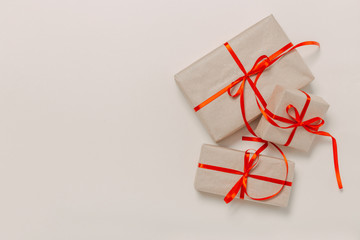 beautiful gift boxes wrapped in paper with a red ribbon and a bow on a beige surface. Top view with...