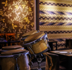 Fototapeta na wymiar Bongo drums in empty restaurant with silk rug on the wall