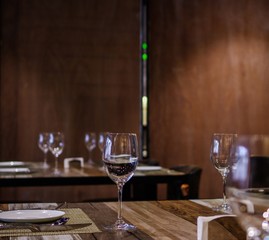 Empty wine glasses on restaurant table with wooden wall background