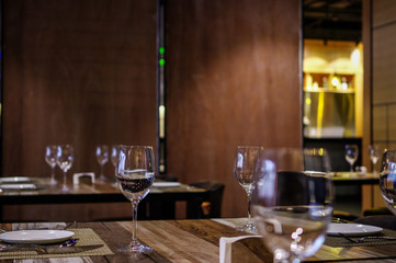 Empty wine glasses on restaurant table with wooden wall background