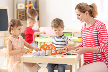 Nursery teacher with cute little children in kindergarten