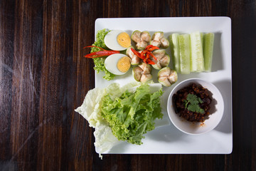 Thai chili paste Nam Prik dip served with long bean, cucumber, white turmeric, boiled egg, eggplant and carrot, Thai traditional food. Selective focus
