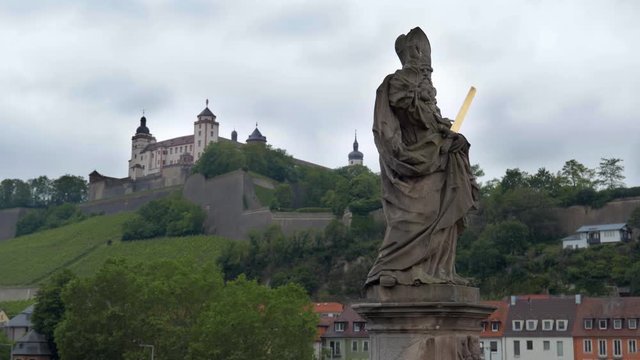 WURZBURG, GERMANY - JUNE 12, 2019: The statue of St Kilian in a the alte Mainbrucke, the old bridge across the Main river in Wurzburg - Bavaria, Germany