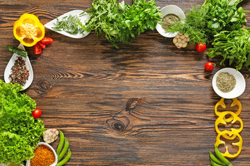 Fresh herbs with vegetables and spices on wooden background