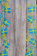 June 6 Sweden independence Day, the concept of the Day of memory of freedom and patriotism. Mini flags with paper confetti on wooden white background. place for text. copy space. vertical