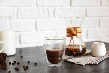 Glass of hot coffee on table near brick wall