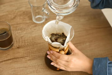 Woman preparing tasty coffee in chemex at table