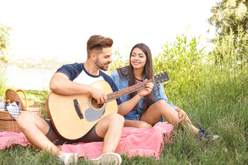 Young couple with guitar on picnic in park