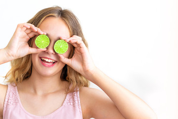 Pretty charming joyful attractive cheerful funny comic positive girl having two pieces of lime, closing two eyes, isolated on white background with copy space for advertisement