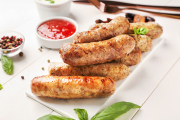 Tasty grilled sausages on white table