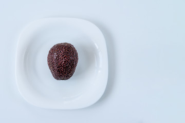 not peeled avocado on the white plate on white table. Time to eat, Breakfast, Lunch time and dinner concept. Diet concept.