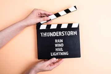 Thunderstorm, Rain Wind Hail Lightning. Female hands holding movie clapper