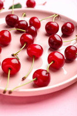 Obraz na płótnie Canvas Plate with ripe cherry on color background