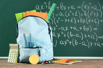 School backpack with stationery on table in classroom