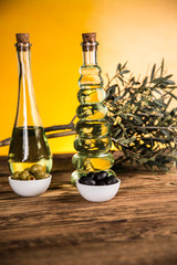 Olive oil, olive tree and green and black olives on a wooden table