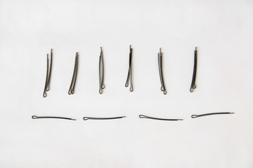 black metal hairpins lie horizontally and vertically exactly on a white background