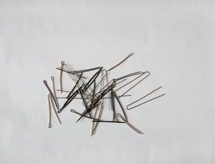 Silver and black metal hairpins are in a large pile on a white background