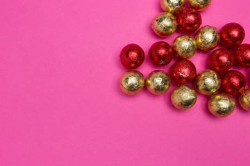 Chocolates in a multi-colored foil on a pink background