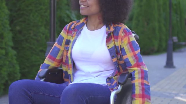 portrait of positive smiling young African American woman disabled in a wheelchair in Sunny Park