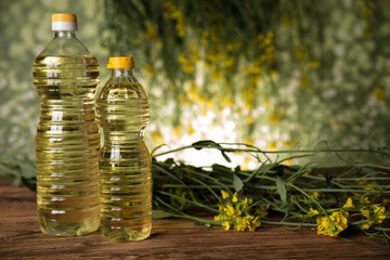 Rapeseed flowers and rapeseed oil in a bottle on the table