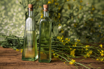 Rapeseed flowers and rapeseed oil in a bottle on the table