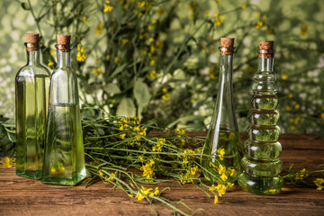 Rapeseed flowers and rapeseed oil in a bottle on the table