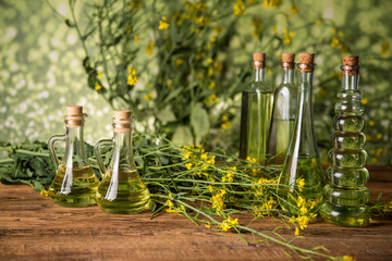 Rapeseed flowers and rapeseed oil in a bottle on the table