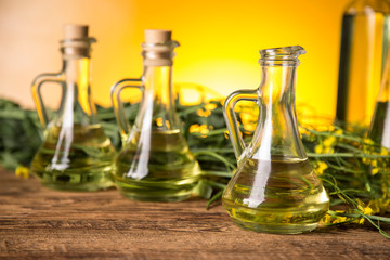Rapeseed flowers and rapeseed oil in a bottle on the table