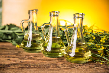 Rapeseed flowers and rapeseed oil in a bottle on the table