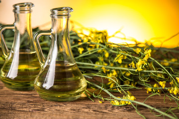 Rapeseed flowers and rapeseed oil in a bottle on the table