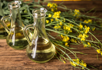 Rapeseed flowers and rapeseed oil in a bottle on the table