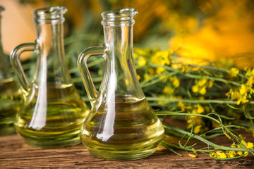 Rapeseed flowers and rapeseed oil in a bottle on the table