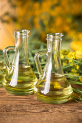 Rapeseed flowers and rapeseed oil in a bottle on the table