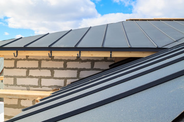 close up view of scaffolding and house under construction with grey folding roof on waterproofing layer