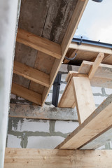 close up view of scaffolding and house under construction with grey folding roof on waterproofing layer