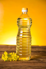 Rapeseed flowers and rapeseed oil in a bottle on the table