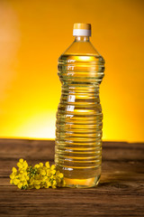 Rapeseed flowers and rapeseed oil in a bottle on the table