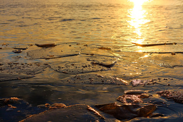 Ice floes in a dramatic sunset color on the lake at winter