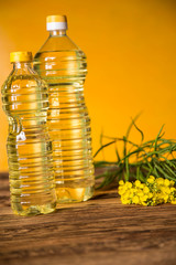 Rapeseed flowers and rapeseed oil in a bottle on the table