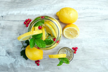 Homemade lemonade with fresh lemons, mint and cranberries. A can of lemonade on a white wooden background. The concept of fresh lemonade, cold juice, heat