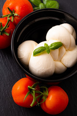 Food ingredient concept organic mozzarella cheese in black ceramic cup with  tomatoes and basil...
