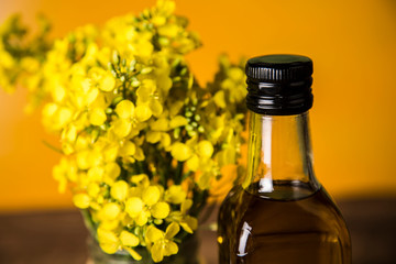 Rapeseed flowers and rapeseed oil in a bottle on the table