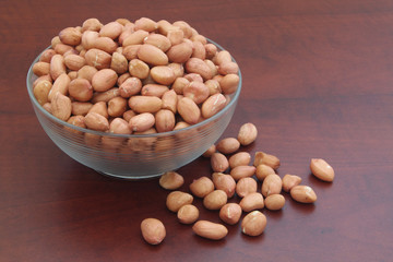 Peanuts on wooden table in glass bowl