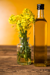 Rapeseed flowers and rapeseed oil in a bottle on the table