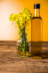 Rapeseed flowers and rapeseed oil in a bottle on the table