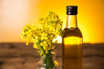 Rapeseed flowers and rapeseed oil in a bottle on the table