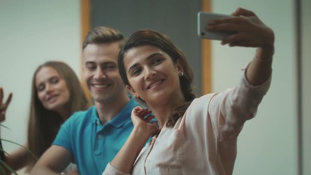 Smiling workers making selfie at coworking. Happy team making victory symbol.